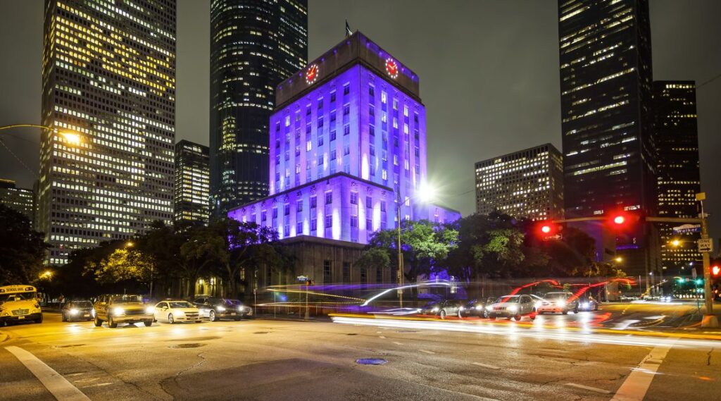 a city at night with purple lights on the building