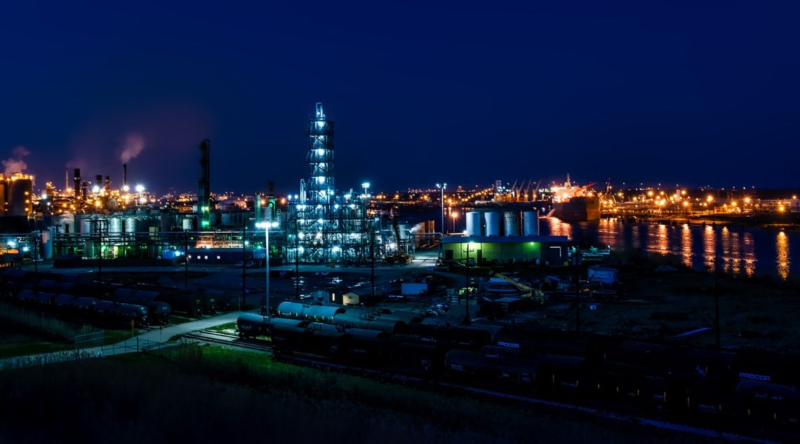 a city at night with a power plant and a river