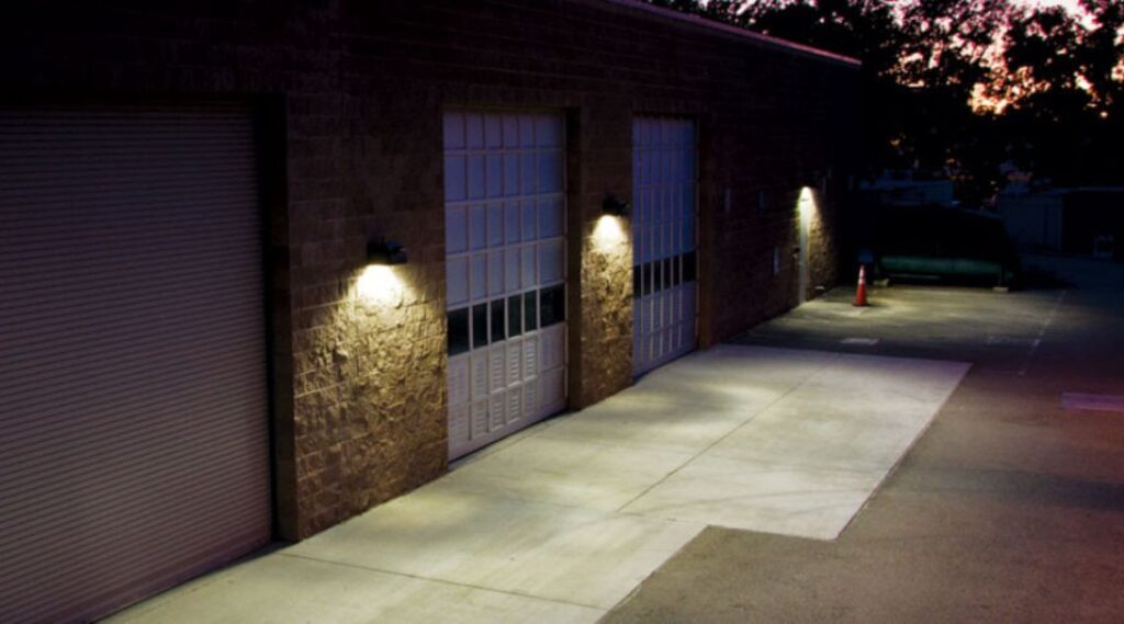 three garage doors with lights on the side of a building