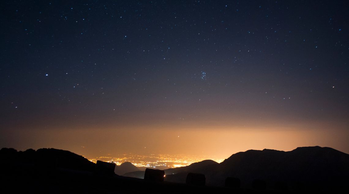 a view of the night sky above the mountains and the city of Las Vegas