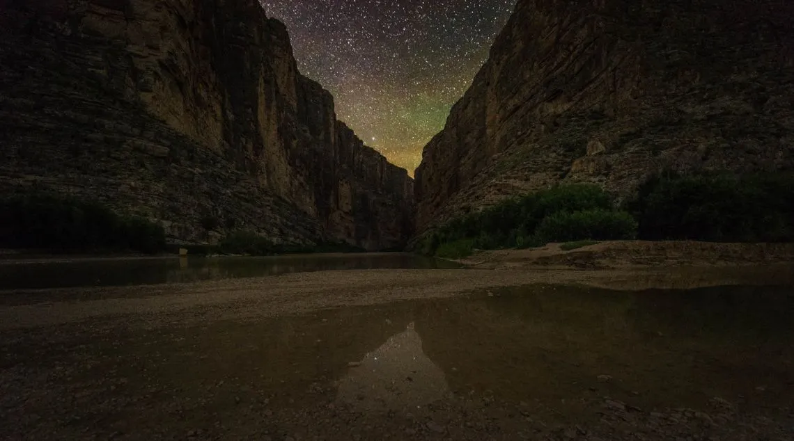 the night sky over a canyon with a river