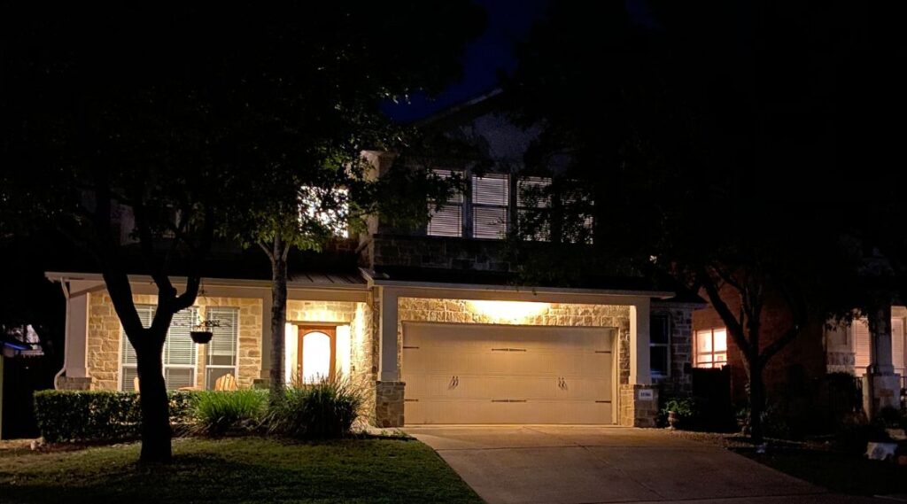 A well-lit home at night featuring a spacious garage, showcasing a warm and inviting atmosphere.