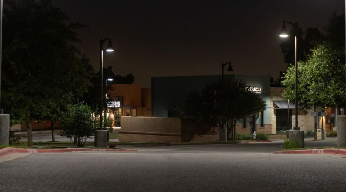 A quiet street at night, illuminated by street lights, with trees providing a natural frame to the softly lit surroundings.